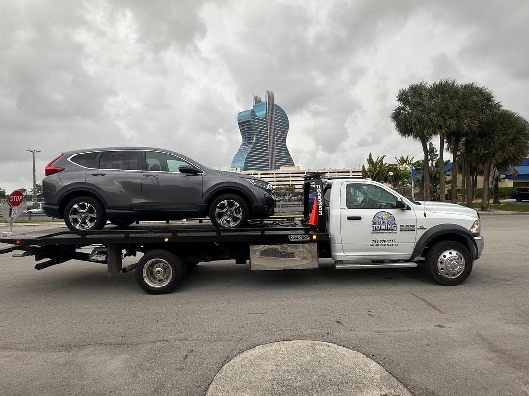 Modern tow truck assisting a car on a road at sunset